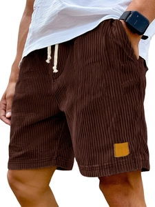 Detailed texture of dark brown corduroy shorts with a yellow leather pocket label
