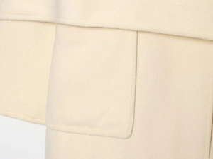 Detail of elegant cream beige wool coat showing premium stitching and pocket texture