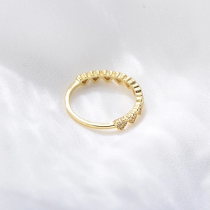 Detail of gold heart-shaped ring with zircon insets on white silk fabric background