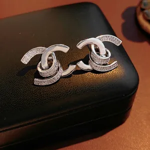 18k gold plated double C earrings with zircon inlay on luxury black leather background