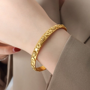 Elegant gold bracelet with celestial sun and moon relief patterns and inset crystals