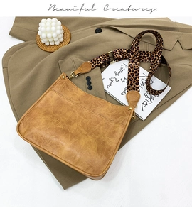 Macro detail of brown leather bag featuring stylish leopard print wide strap and brass hardware