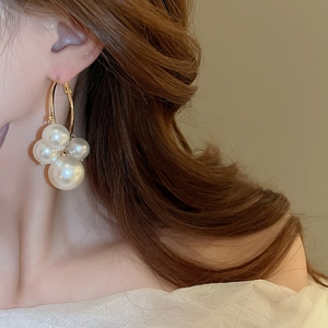 Élégant grappe de perles d'imitation blanches sur créole dorée portée par un mannequin