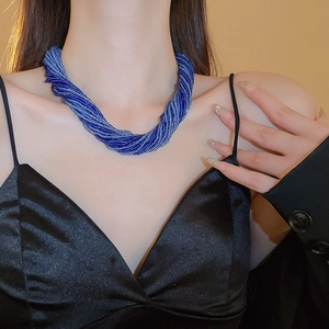 Dettaglio della collana di perline blu scuro multistrato intrecciata sul collo