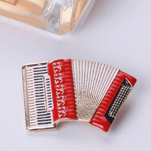 Detailed close-up of an accordion brooch with red and white enamel on a gold-tone metal base