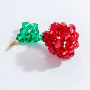 Detail view of handmade faceted red and green crystal glass bead pendant with gold ring