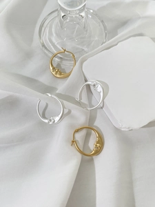 Detail of moon face hoop earrings in gold and silver finish with crystal accents
