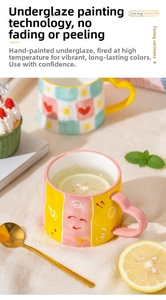 Detail of a ceramic mug featuring a heart-shaped handle and hand-painted smiley face design