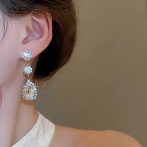 Close-up of a vintage teardrop earring featuring sparkling rhinestones on a model's ear