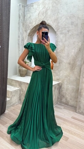 Detail of elegant dark green pleated evening gown featuring a high waist and ruffle sleeves