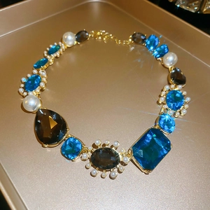 Detailed view of vintage gold necklace with blue and brown crystals and white pearls