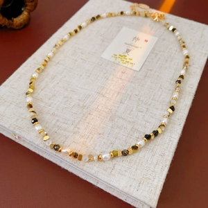 Detailed view of freshwater pearl necklace with vintage mixed beads on a linen book cover