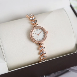 Close-up of rose gold mermaid watch with crystal-encrusted leaf strap on display pillow