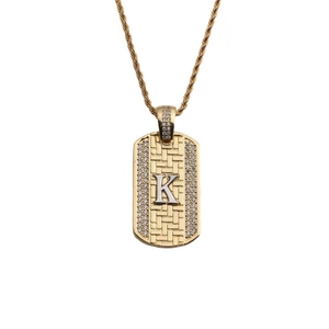 Gros plan détaillé d'un pendentif dog tag doré avec lettre K et zircons brillants