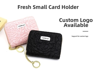 Detail view of pink and black rose-embossed accordion card wallets with gold keychains
