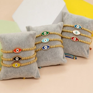 Colorful Evil Eye beaded bracelets with gold beads on grey velvet jewelry pillows