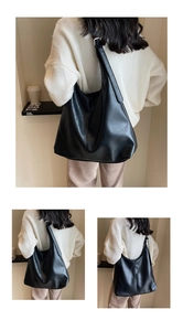 Detailed view of casual black soft leather tote bag worn by a model in a minimalist setting