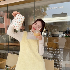 Close-up of a quilted floral makeup bag with a zipper, held by a model in soft light