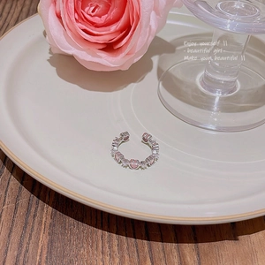 Detail of adjustable silver ring with pink heart zircons and white crystals on a plate