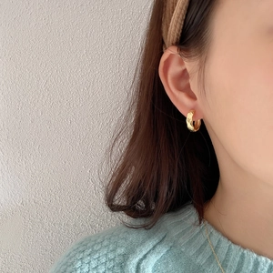 Close-up of minimalist gold geometric hoop earring with diamond pattern on model ear