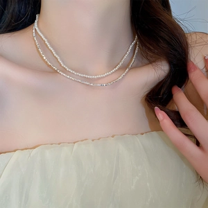 Detail of double-layer necklace with white pearls and silver-tone crushed metal chain