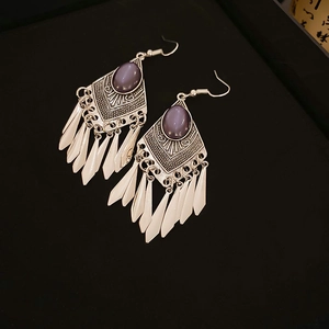 Macro detail of retro silver tassel earrings with purple stones and carved patterns