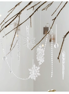 Close-up of clear acrylic snowflake and icicle ornaments hanging on a winter branch