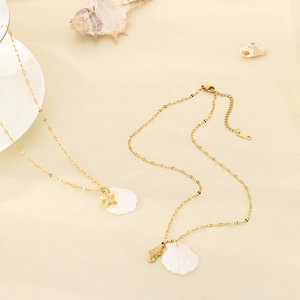 Detail of 18K gold plated necklace featuring white shell and starfish charms on a fine chain