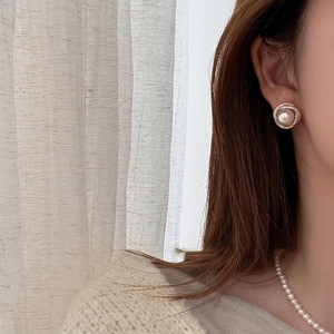Close-up of elegant rose gold pearl stud earring with sparkling zircon halo on model ear