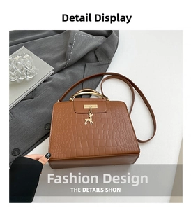Detail view of brown crocodile texture handbag with gold circular handle and deer pendant