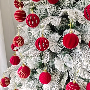 Gros plan de boules de Noël en velours rouge avec motifs dorés sur sapin enneigé