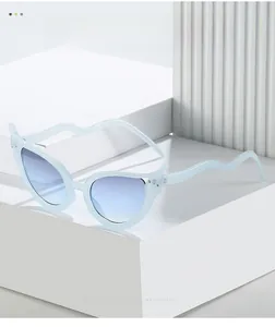 Detail of light blue cat eye sunglasses with wavy arms and blue gradient lenses
