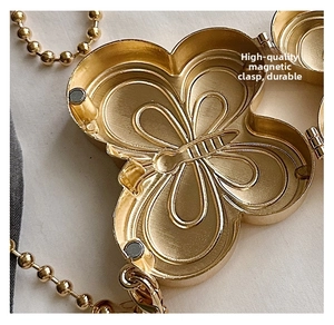 Macro detail of golden butterfly metal bag with magnetic closure and embossed pattern