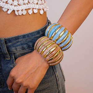Detail of chunky acrylic stretch bracelets in blue and nude gold on a woman wrist
