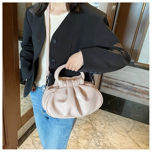 Detail of pink pleated cloud bag with round handle and adjustable shoulder strap