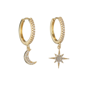 Close-up of gold moon and star earrings with pavé-set zircons on white background