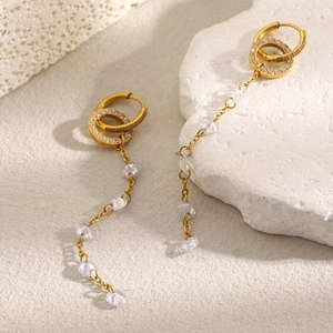 Detailed view of long gold tassel earrings with zircon circles and crystal beads on stone