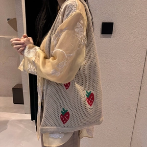 Detail of a beige knit strawberry tote bag showing intricate crochet texture and pattern