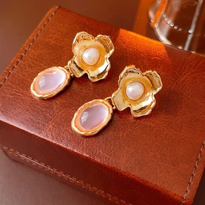 Vintage gold petal earrings with pearls and purple stone drops on a leather jewelry box