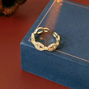 Macro shot of gold plated open ring with cubic zirconia stones on blue textured box