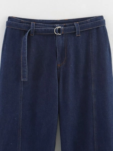 Détail du pantalon en jean bleu foncé à taille haute avec ceinture en tissu et boucle argentée