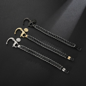 Détail d'un bracelet en cuir noir tressé avec fermoirs en acier or, argent et noir