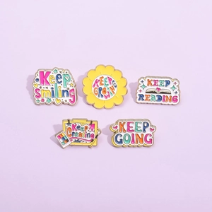 Set of five motivational enamel pins with Keep Smiling and Growing text on purple background