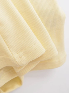Gros plan sur la texture du tricot côtelé jaune pâle et les détails de couture fins