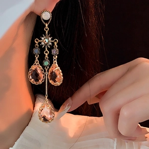 Detail of golden tassel earrings with star elements and champagne teardrop crystals