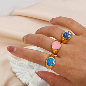 Detailed close-up of three 18k gold plated enamel rings with cosmic sun and planet motifs