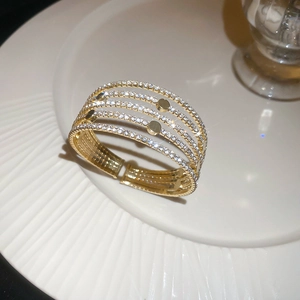 Détail d'un bracelet doré multicouche avec zircons et perles sur une assiette en porcelaine