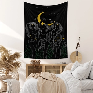 Close-up of bohemian black tapestry with gold moon and female silhouettes on a cozy bedroom wall