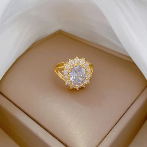 Close-up of golden ring with oval clear gemstone on beige jewelry box with silk fabric