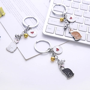 Detailed view of metal cat keychains in white, brown, and black with golden bells